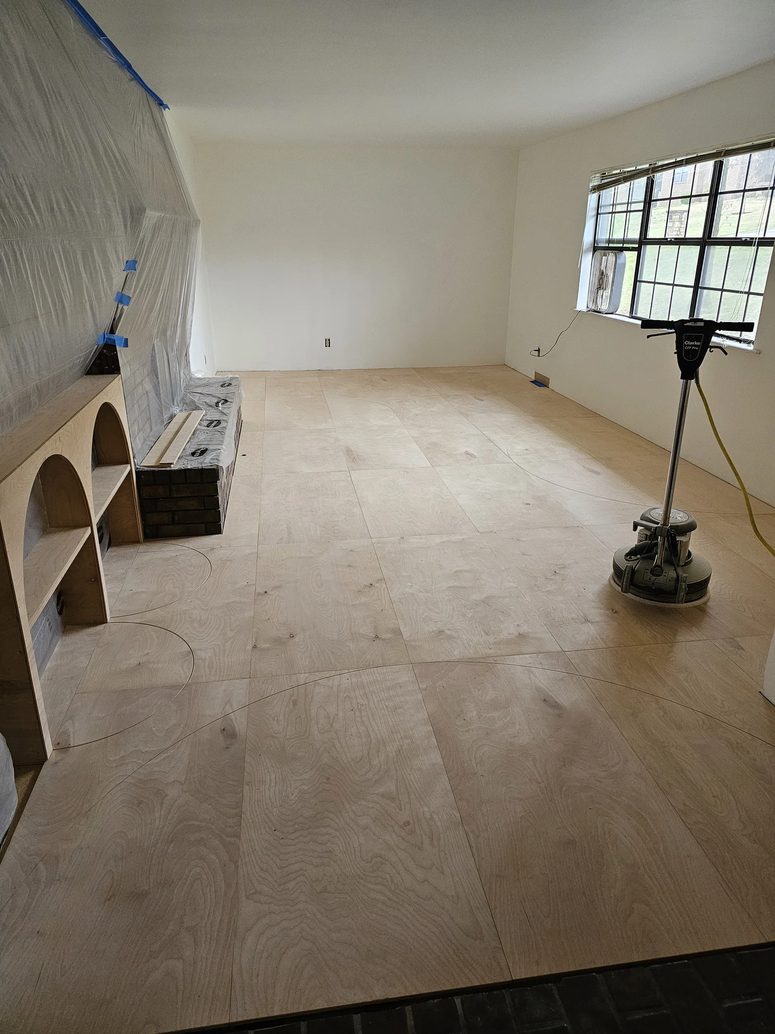 The room stripped to subfloor around the stone fireplace, before the new floor.