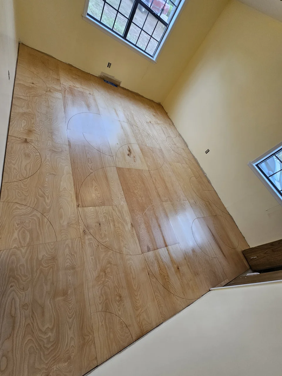 Pencil layout arcs scribed across raw birch plywood sheets before cutting.