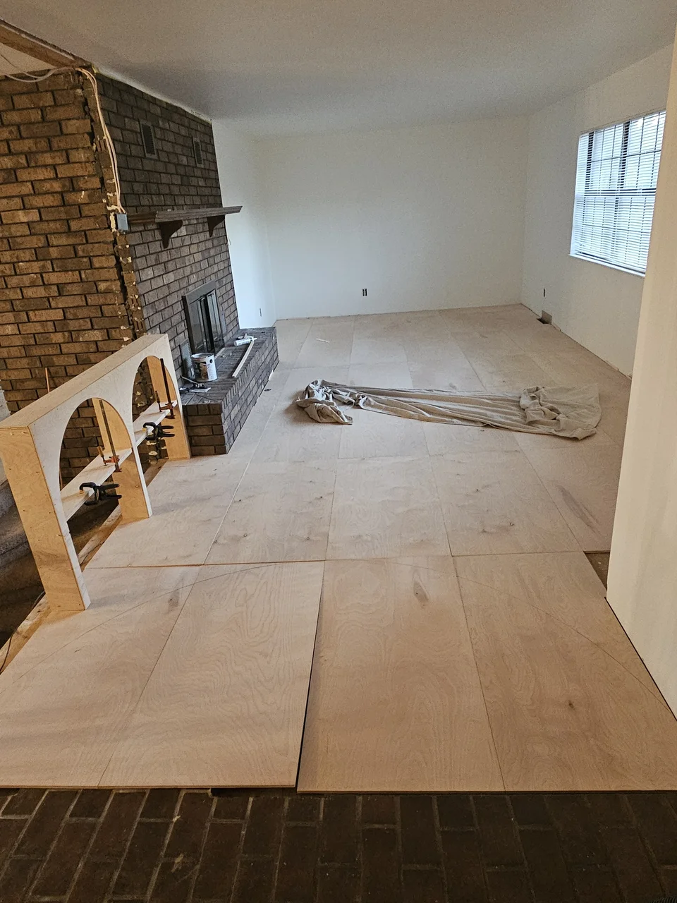 A floor buffer in use on the finished birch floor under plastic sheeting.