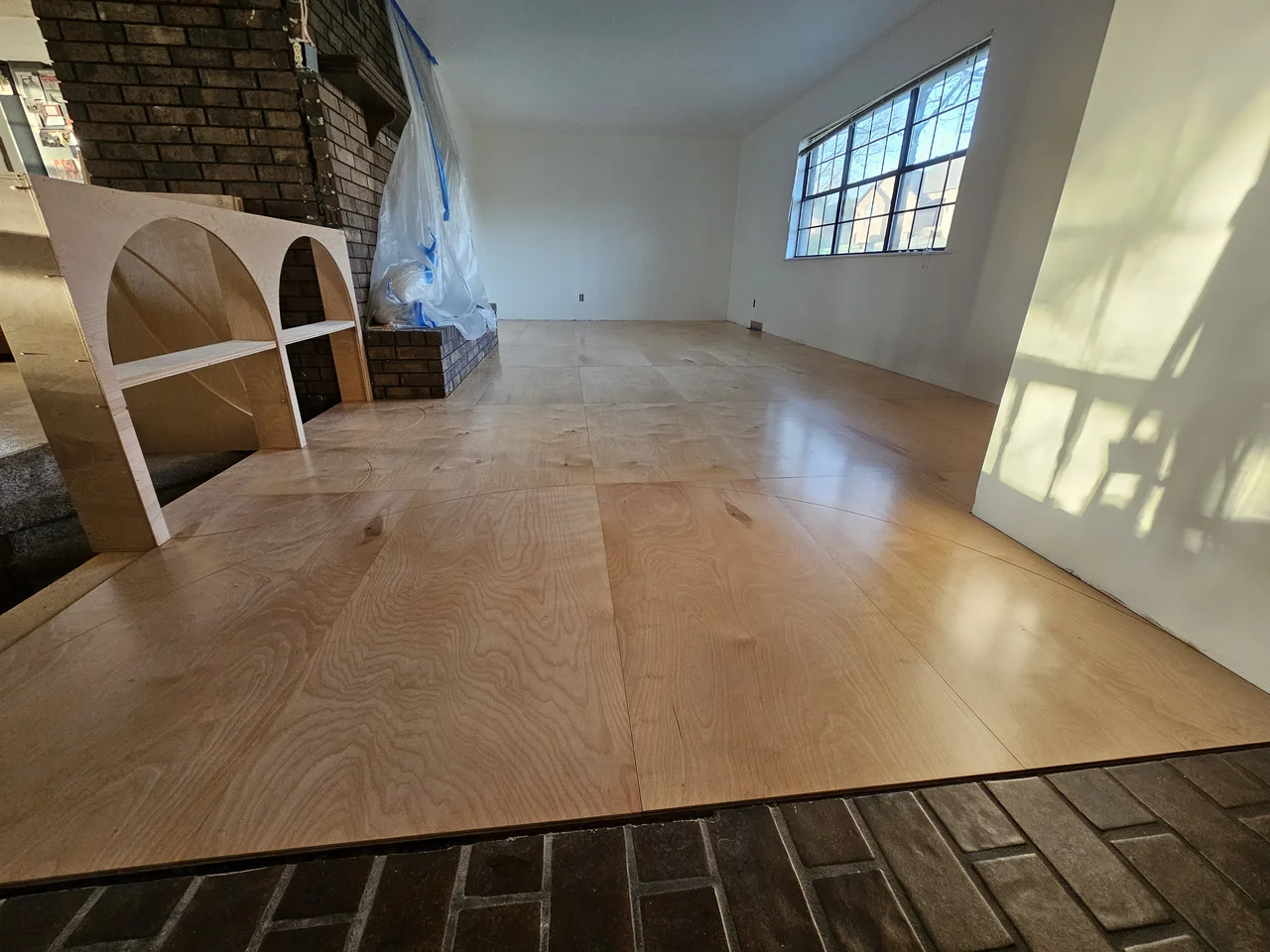 The finished birch floor with twin arches at left and raking window light down the room.