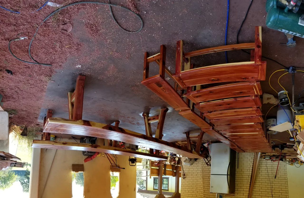 Finished cedar tables under gloss finish with pegged trestle joinery catching light.
