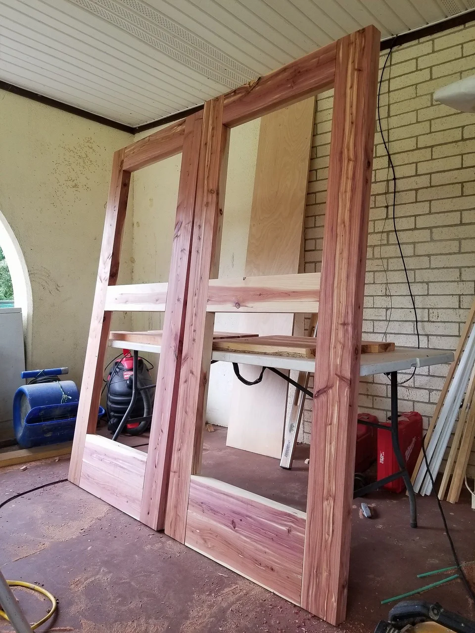 Cedar door frames and panels standing in the shop during construction.