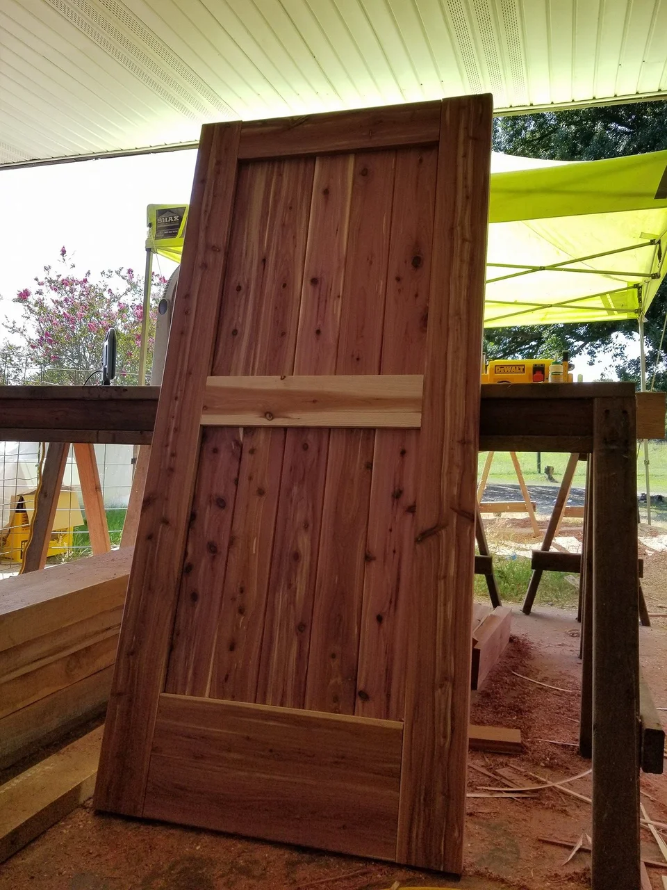 A completed ledged-and-braced cedar door standing outdoors.