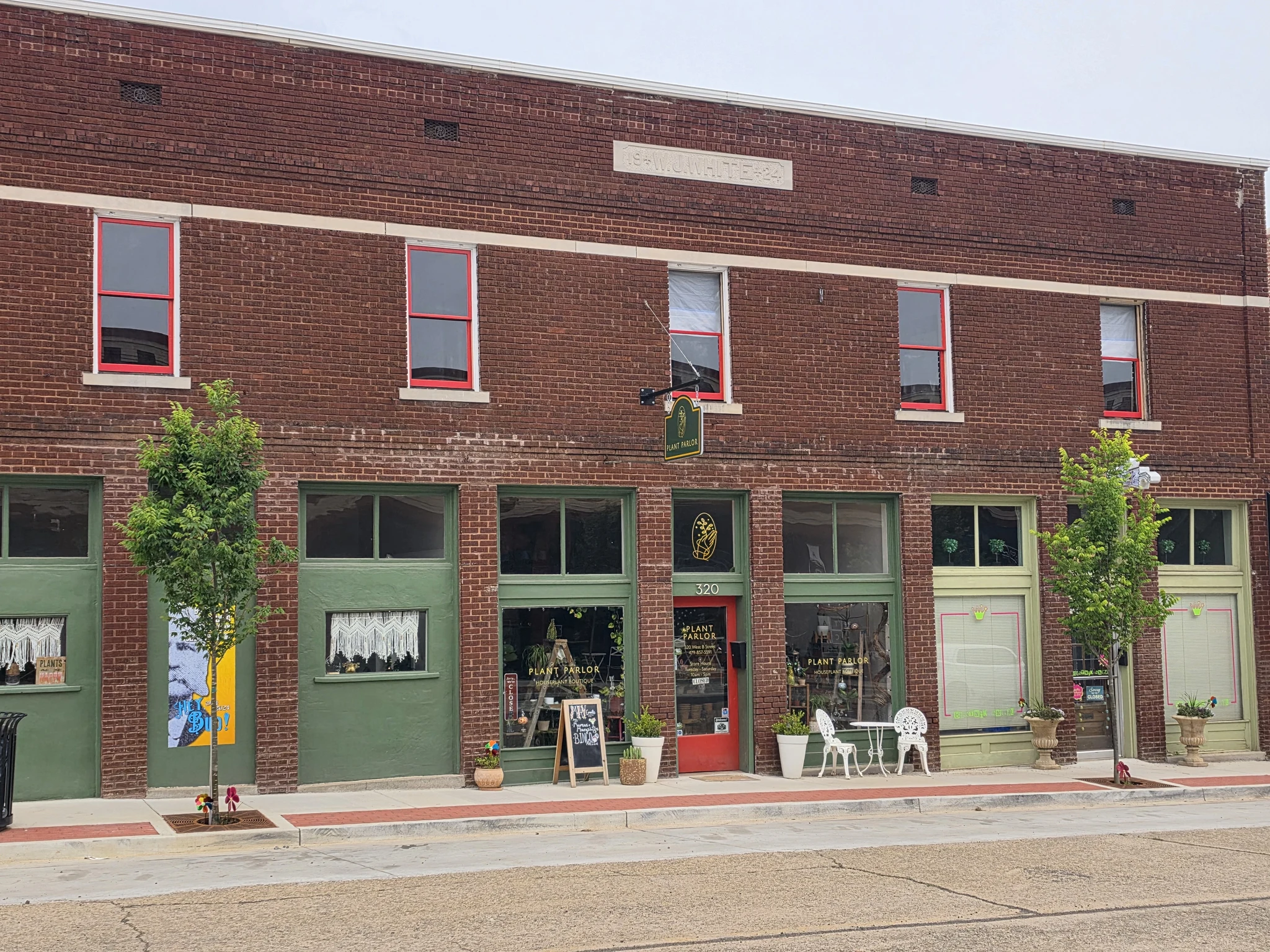 The finished historic brick commercial building with red sash windows and green storefront.