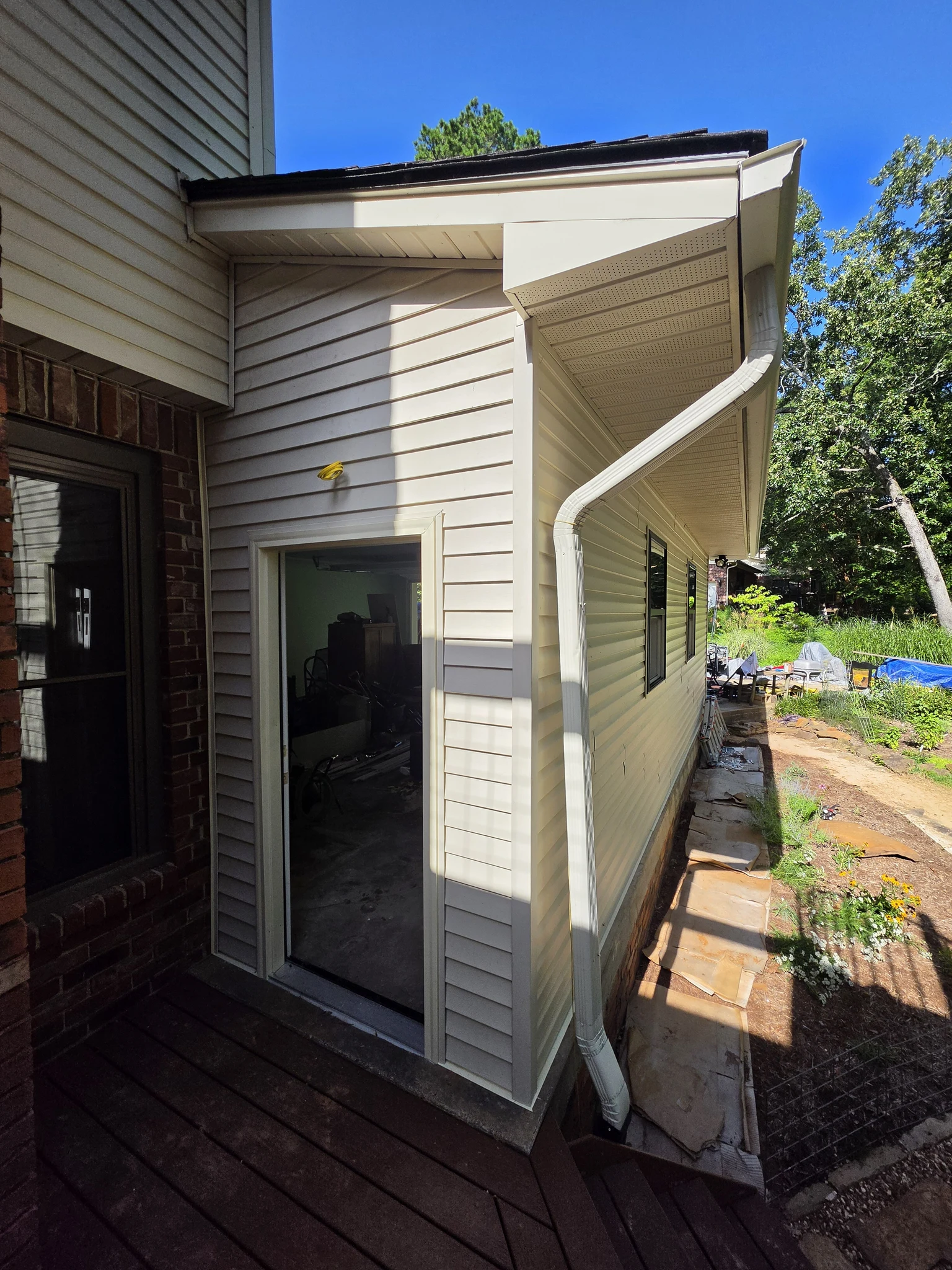 The exterior with new siding, downspout and a sliding door installed.