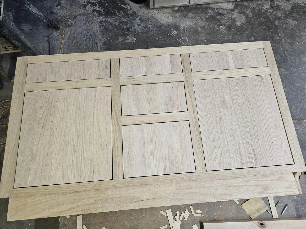Matching cerused cabinet doors laid out flat in the shop.