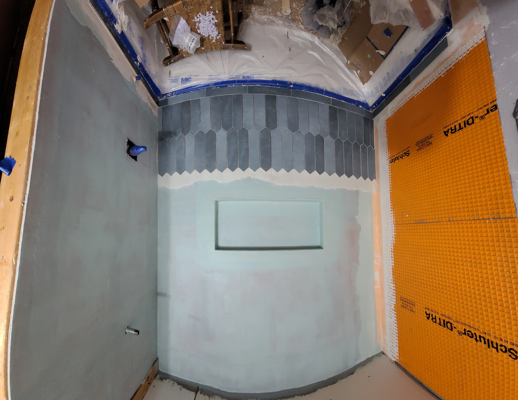 A shower wall with orange waterproofing membrane and tile starting at the base.
