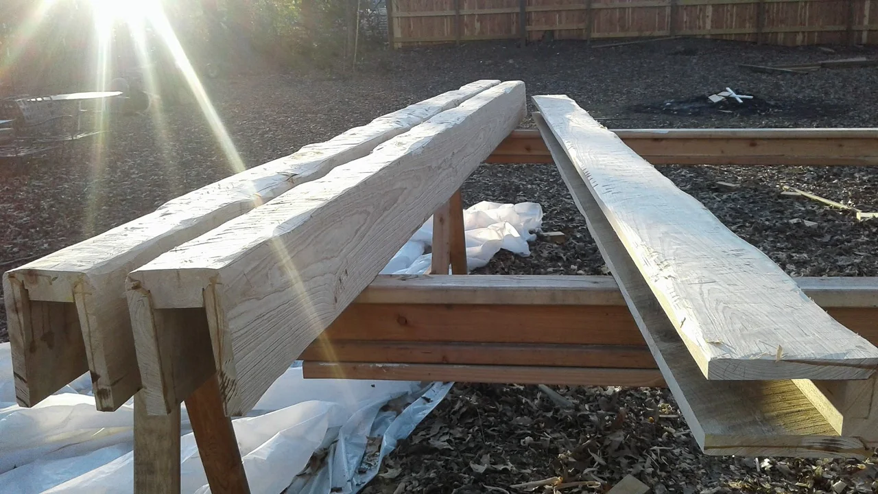 Shaped beams resting across sawhorses in the sun before installation.