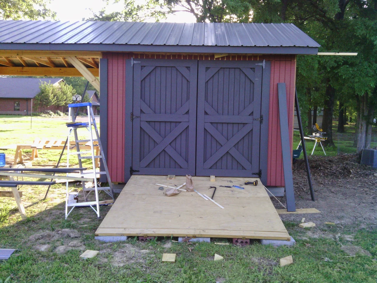 The shed painted red with dark trim and doors installed.