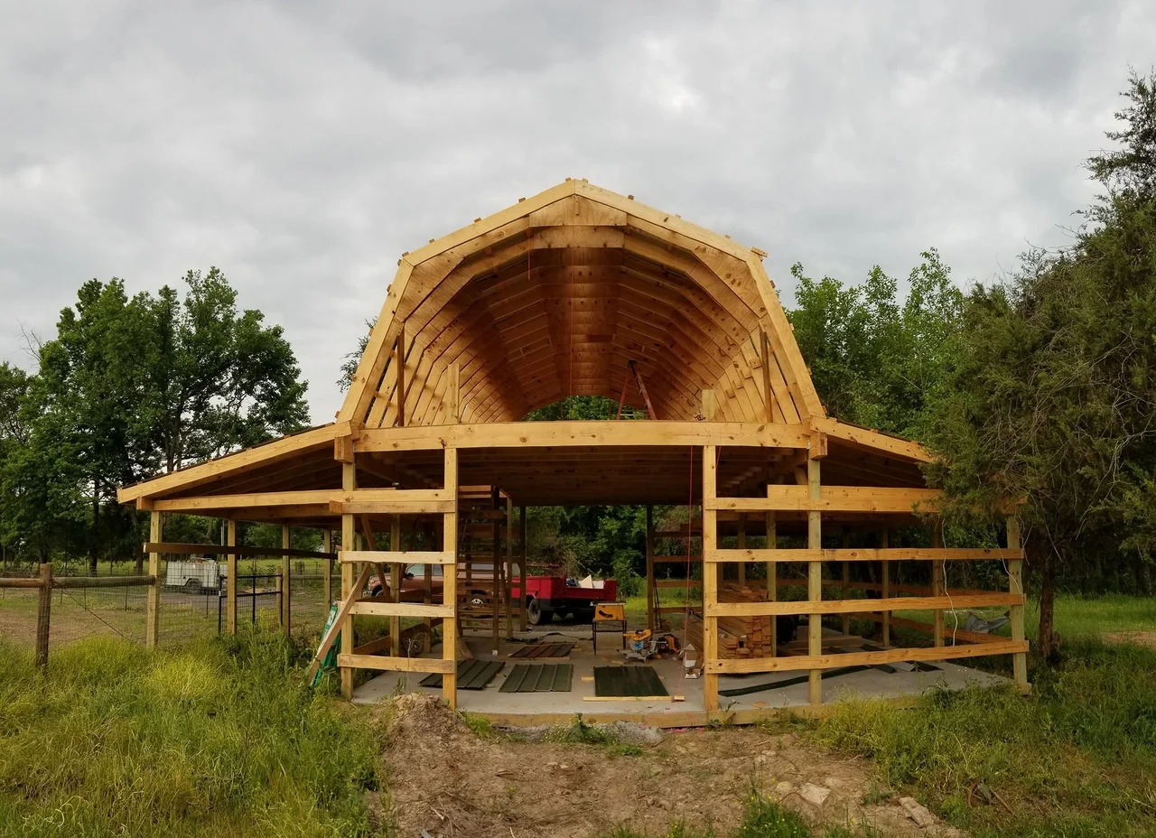 The raised gambrel trusses seen through the open barn structure.