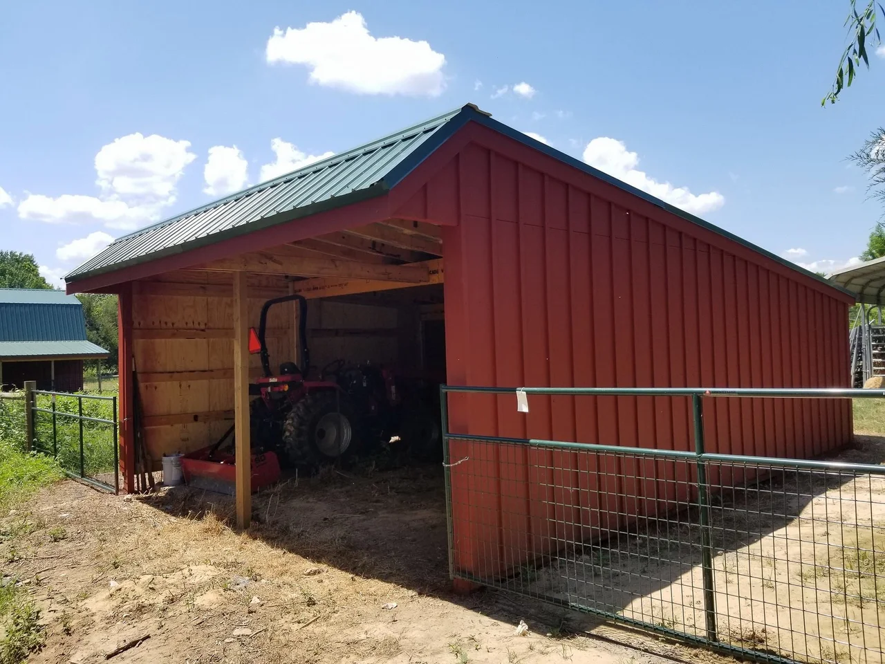 The shed-roofed barn built alongside, with a tractor parked beneath it.