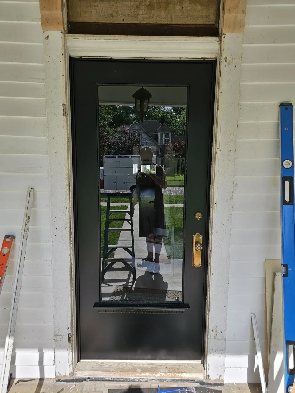 The completed entry door installed in its opening with glass and brass hardware.
