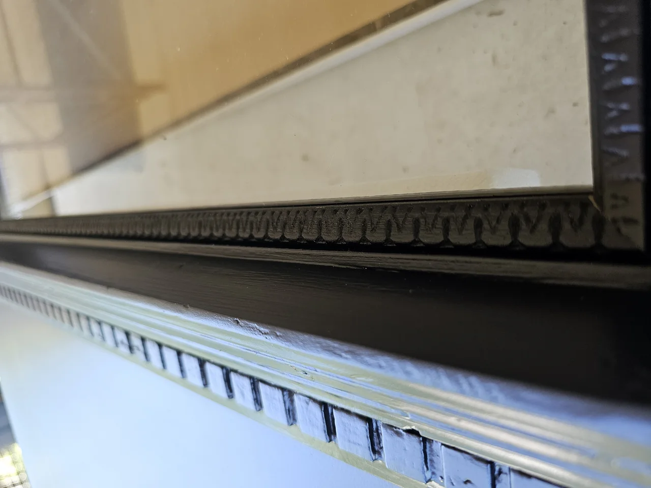 The finished door painted black, with the carved moulding catching raking light.