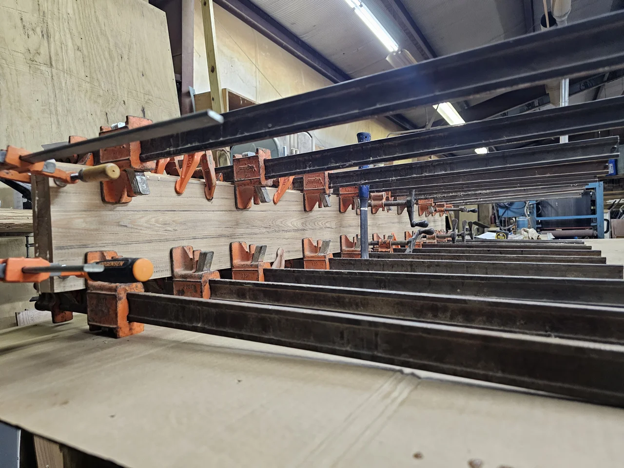 Wide view of the door glue-up under clamps in the shop.