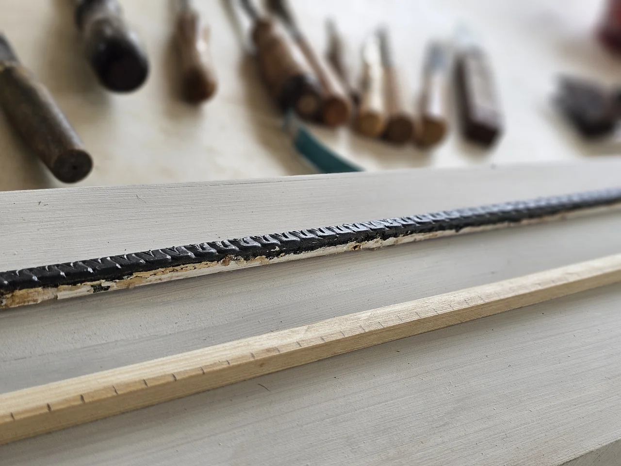 A hand-carved moulding run with chisels behind it.