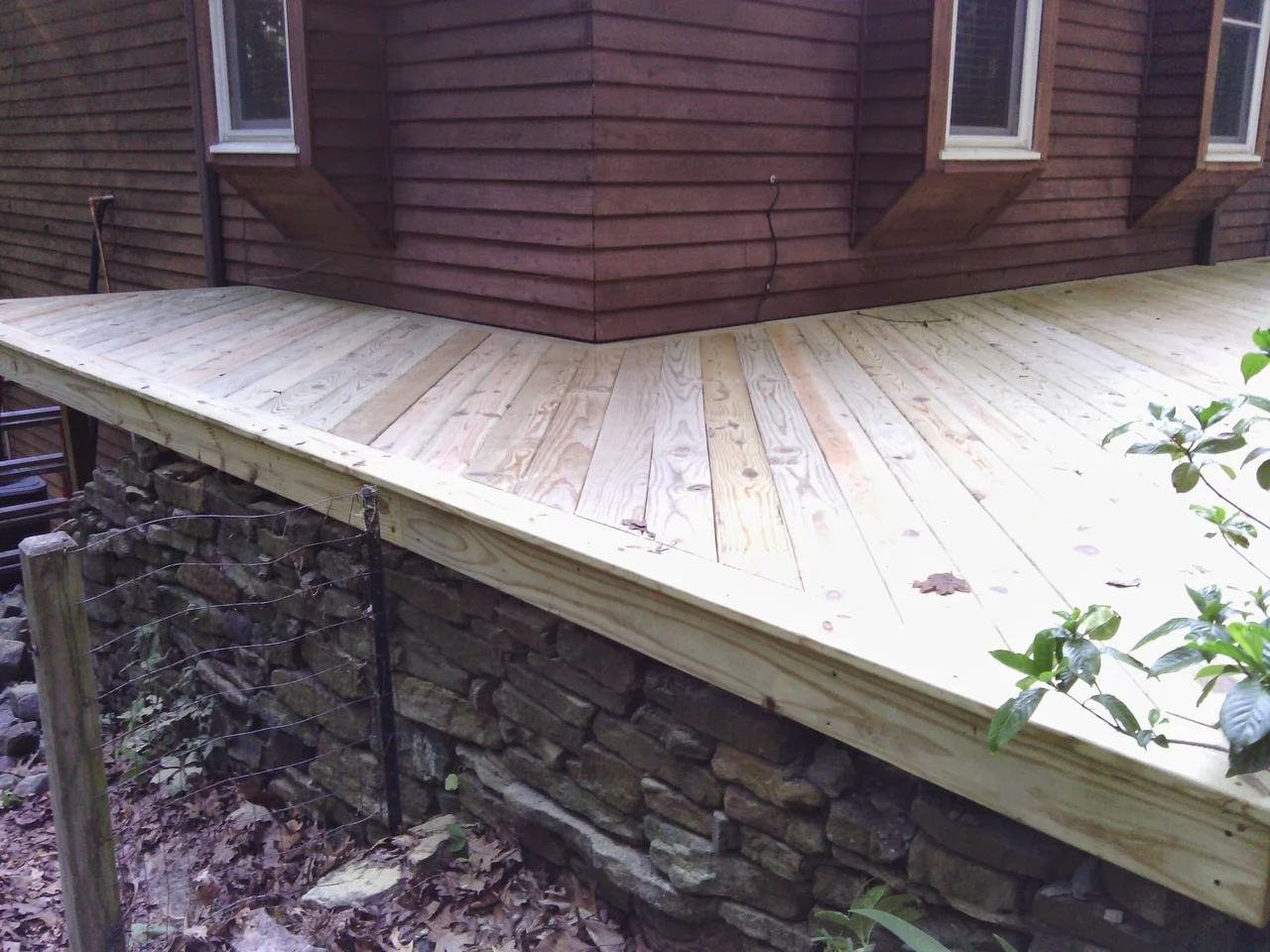 The deck edge running over the existing dry-stack stone foundation.