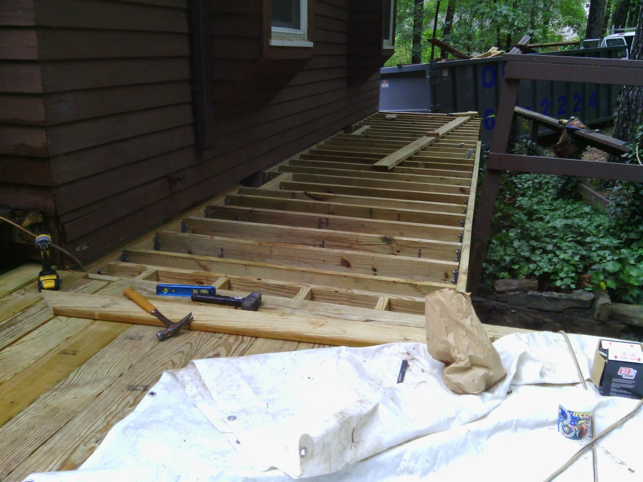 New ledger and joists framed above the existing stone foundation at the entry.