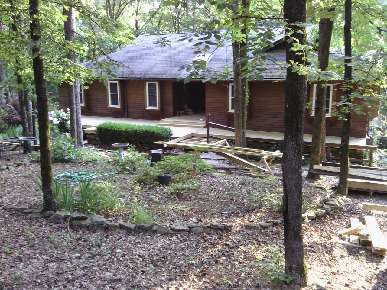 The house set among trees with the deck running along its side.