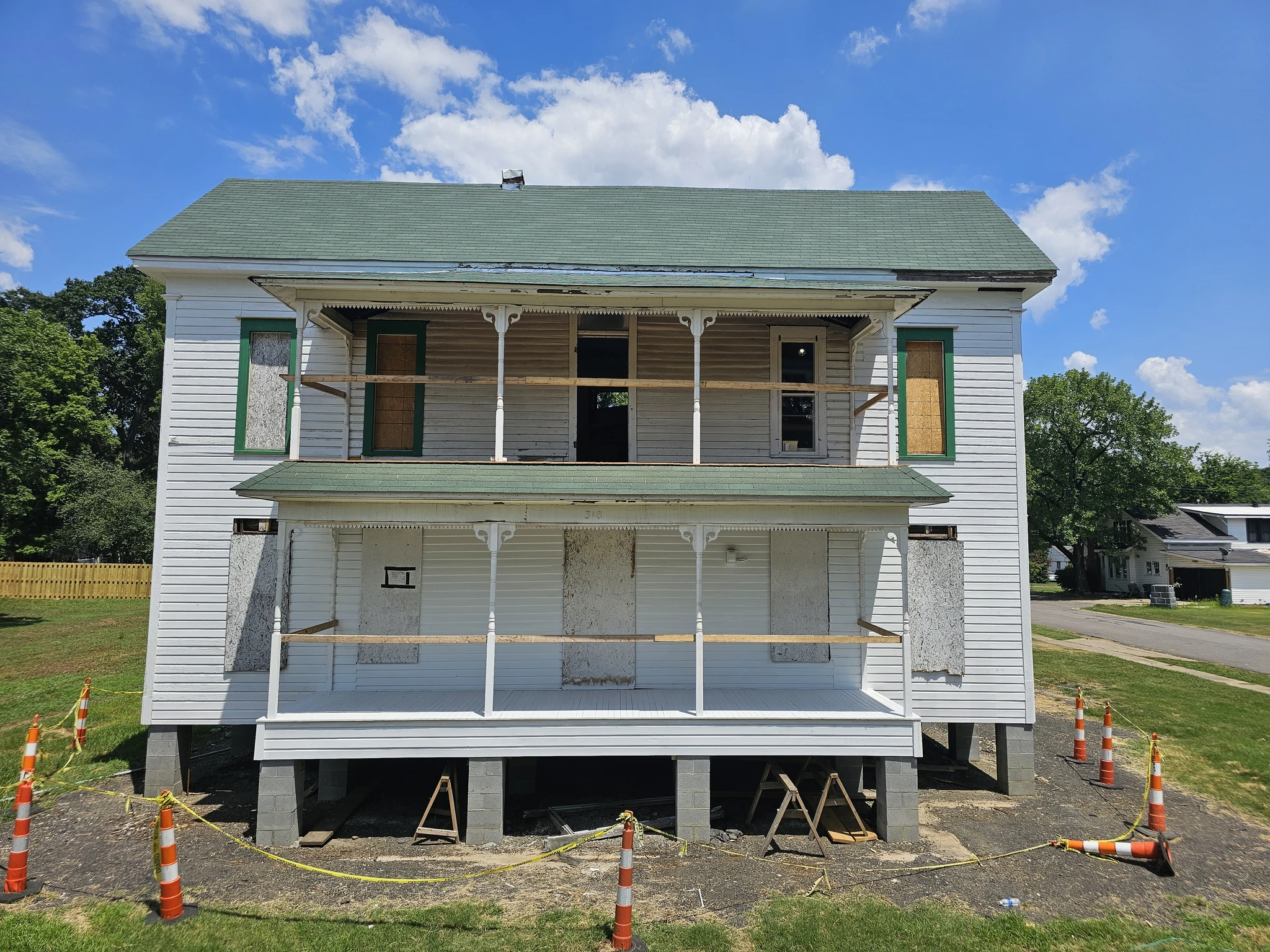 A historic house boarded up and supported on cribbing before restoration work.