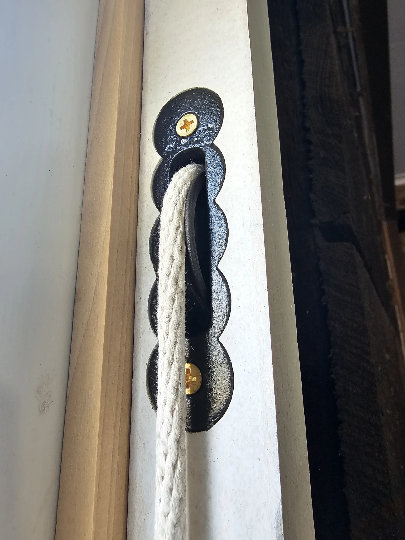 A restored sash pulley and cord installed and working in a window jamb.