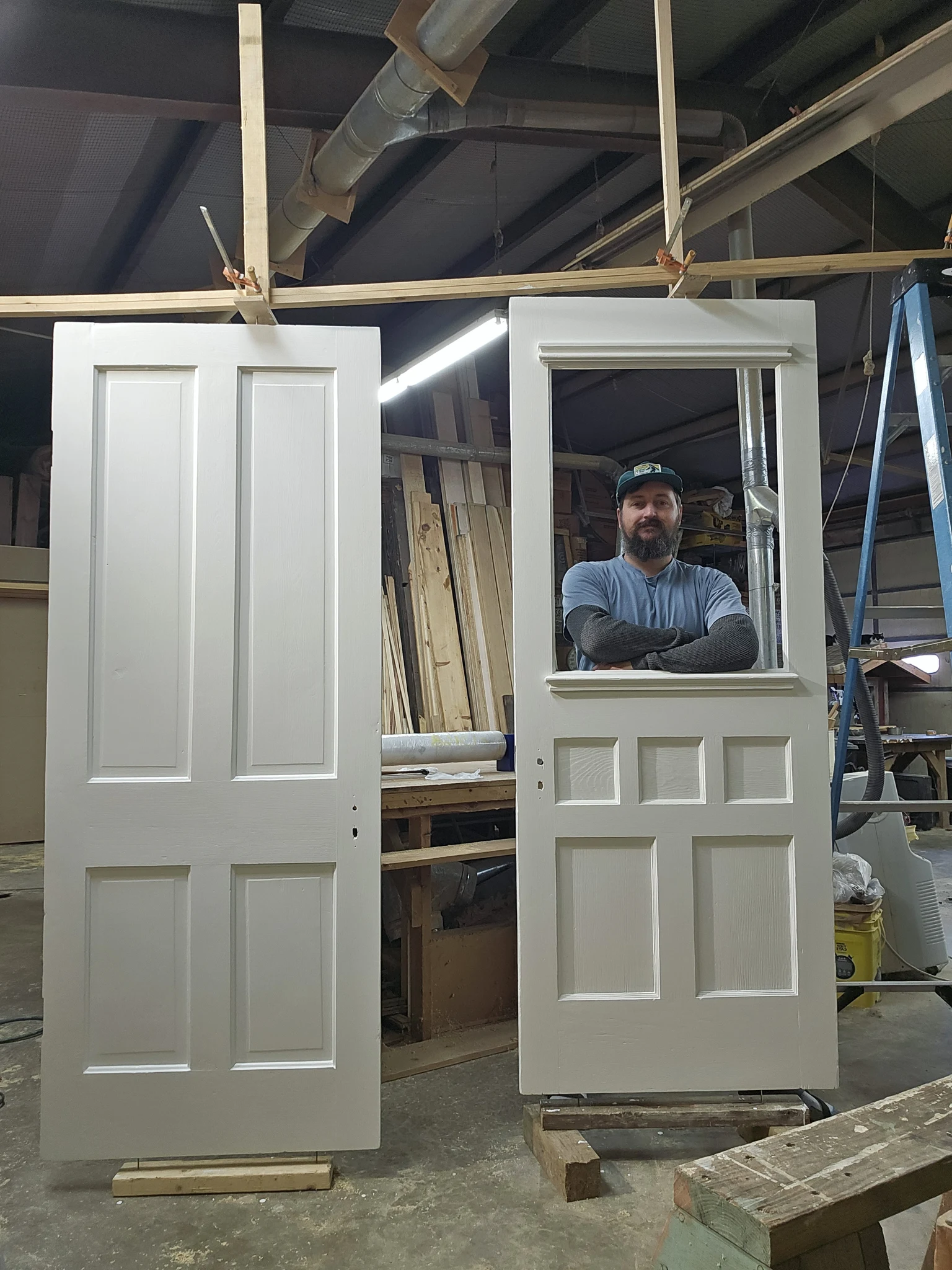 A person standing in the opening of a finished door, with two completed doors hung.