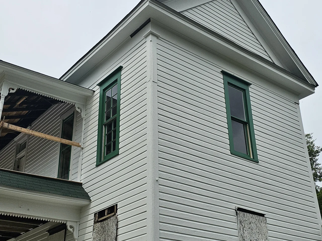 New window sashes installed in the building, green trim against white siding.