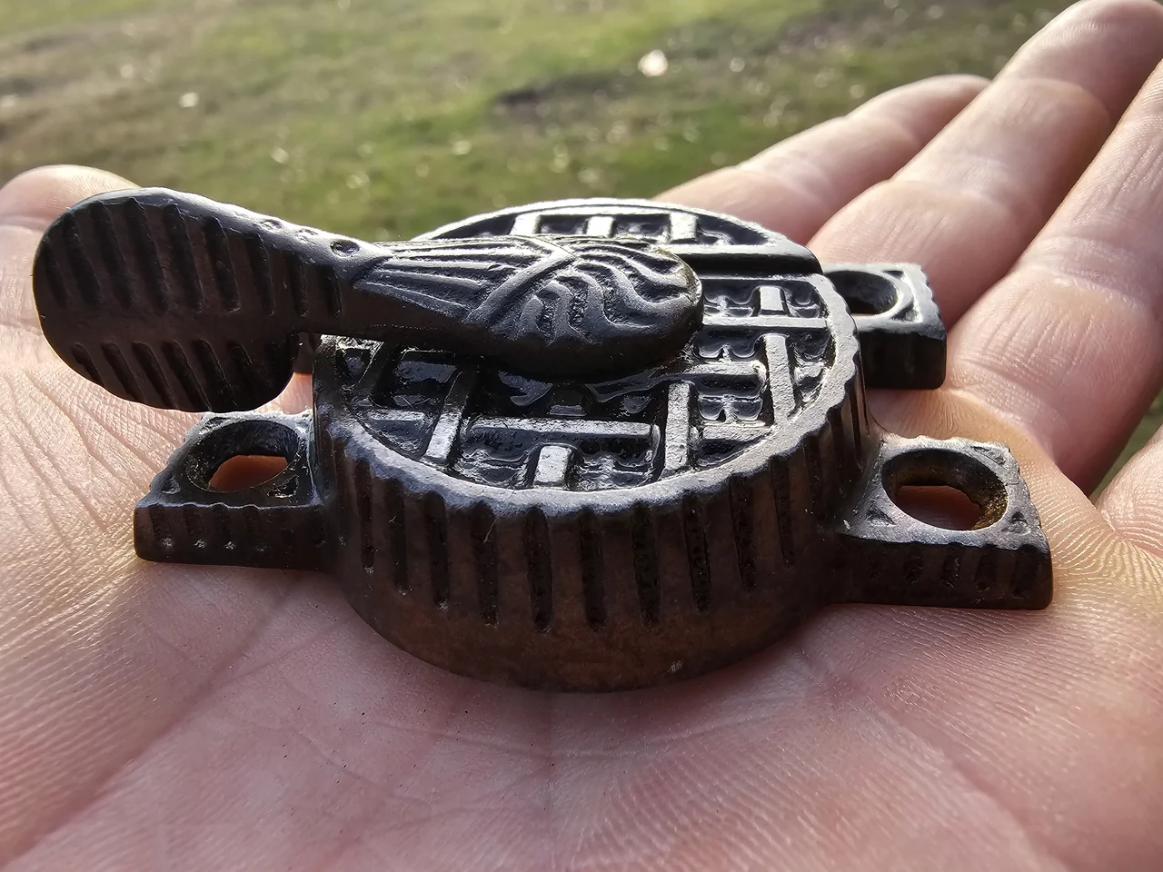 A cast-iron sash lift held in the hand, cleaned and ready to reuse.