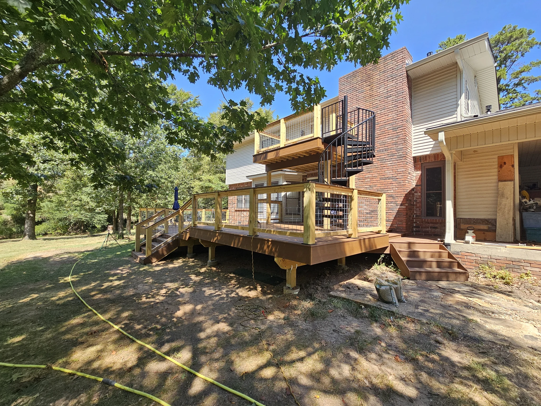 The completed multi-level deck seen from the yard through tree canopy.