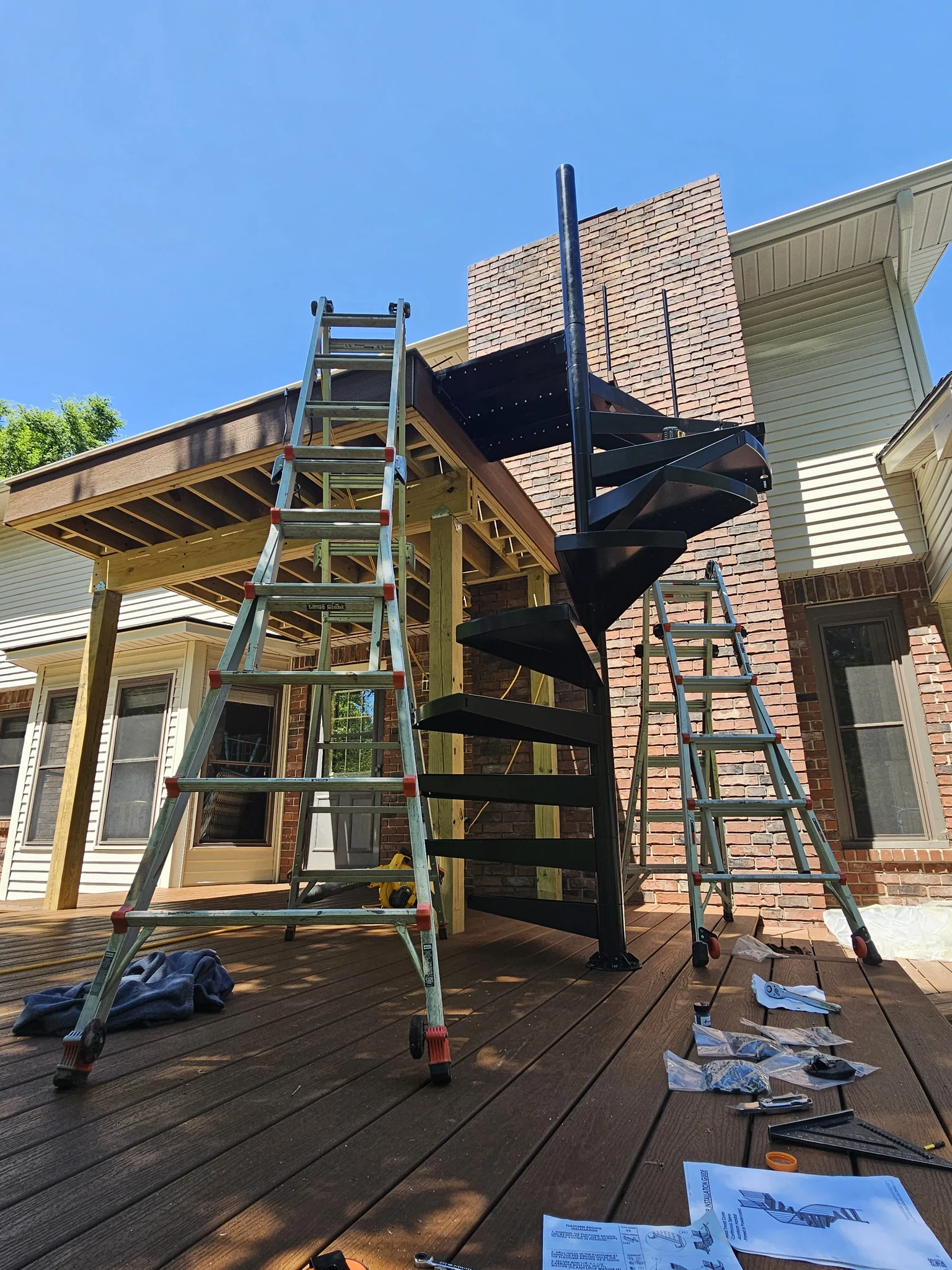 The black spiral stair set into position, treads fanned from ground level to the upper deck.