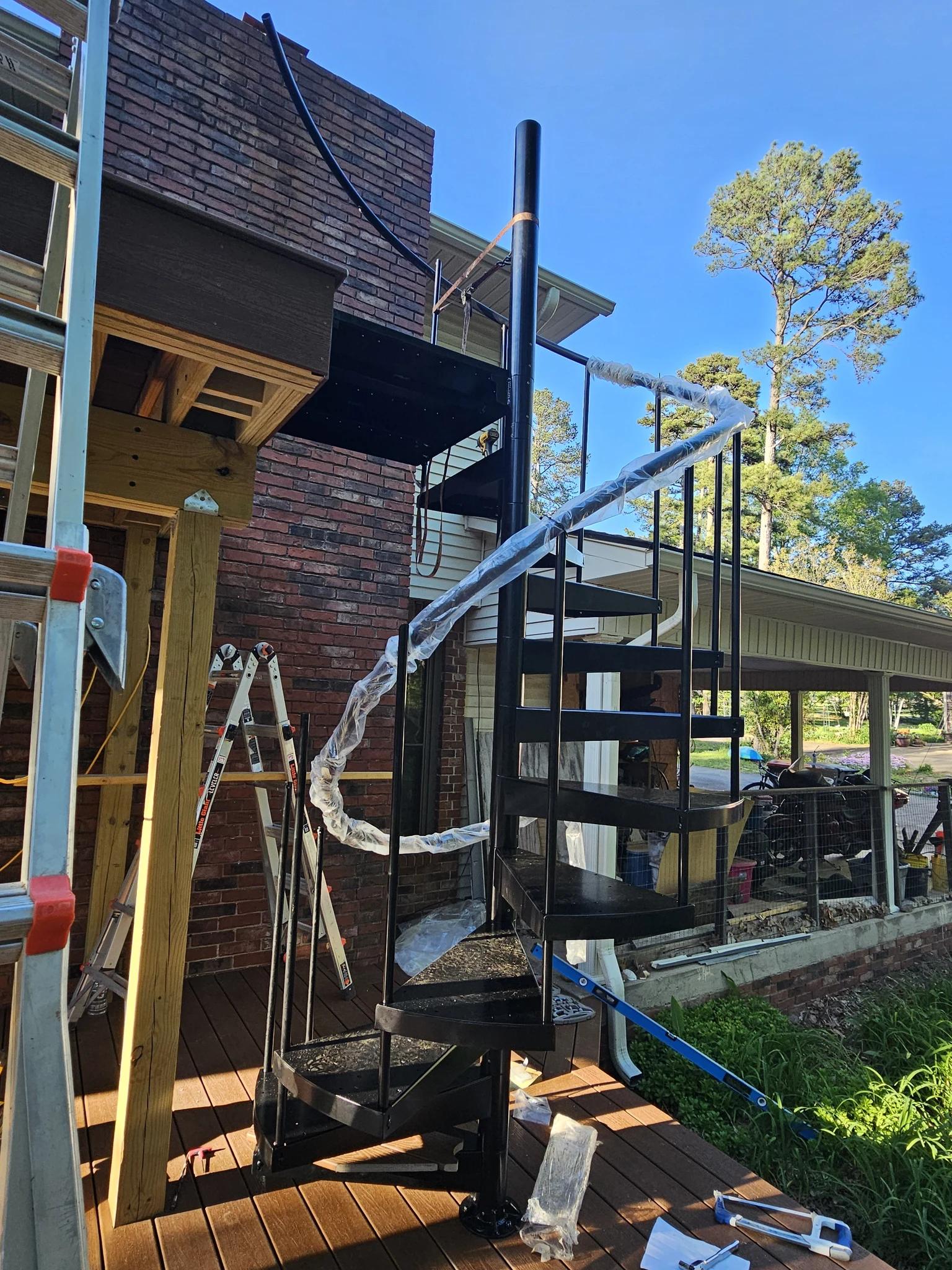 The curved handrail sections still in protective wrapping beside the stair before fitting.