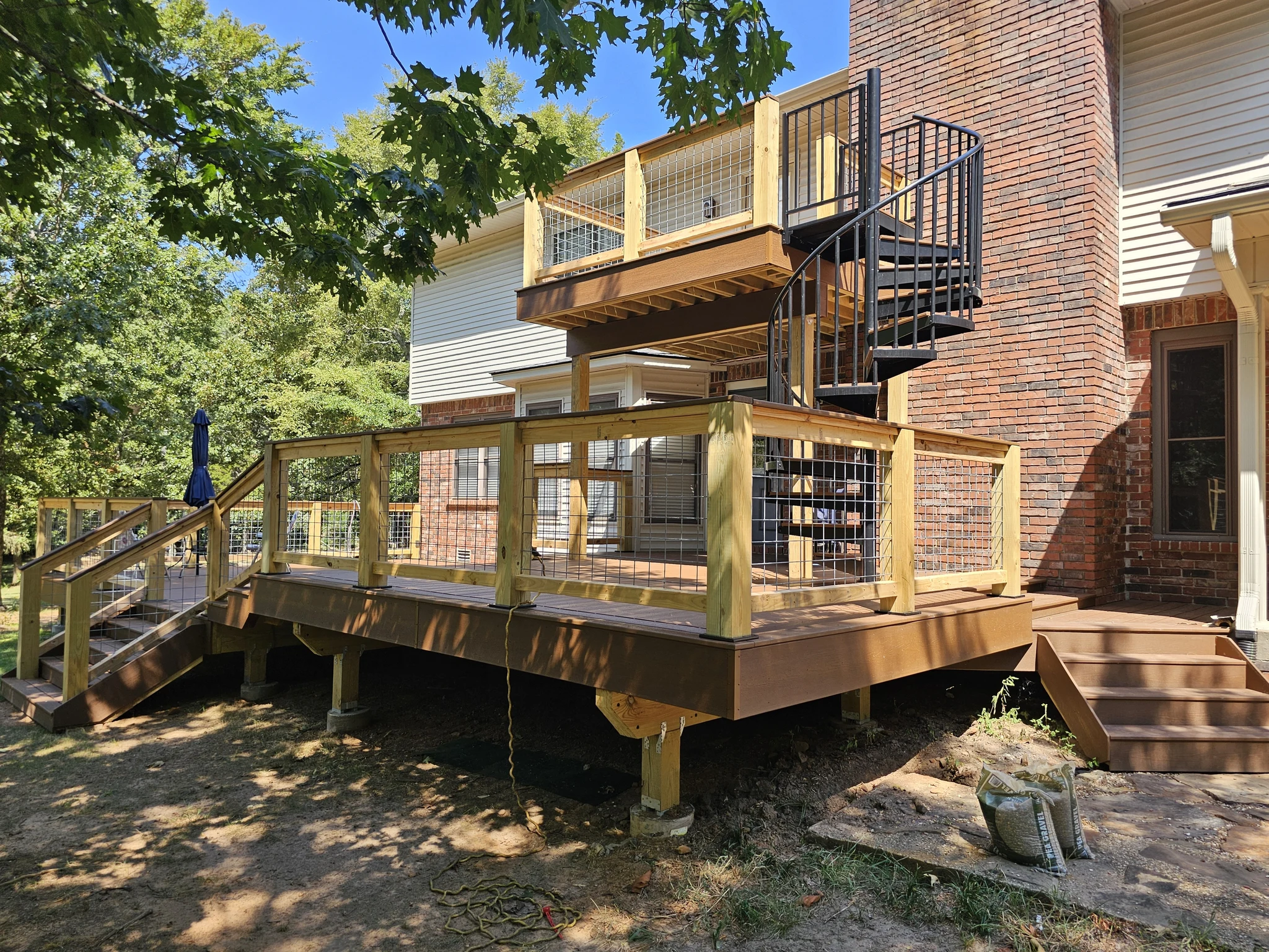 The finished multi-level deck with railing and the spiral stair connecting both levels.
