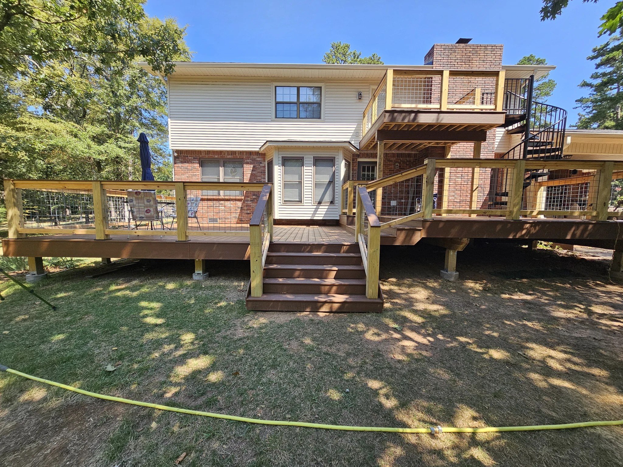 The full sunlit rear elevation showing both deck levels, railing, stairs and spiral stair.