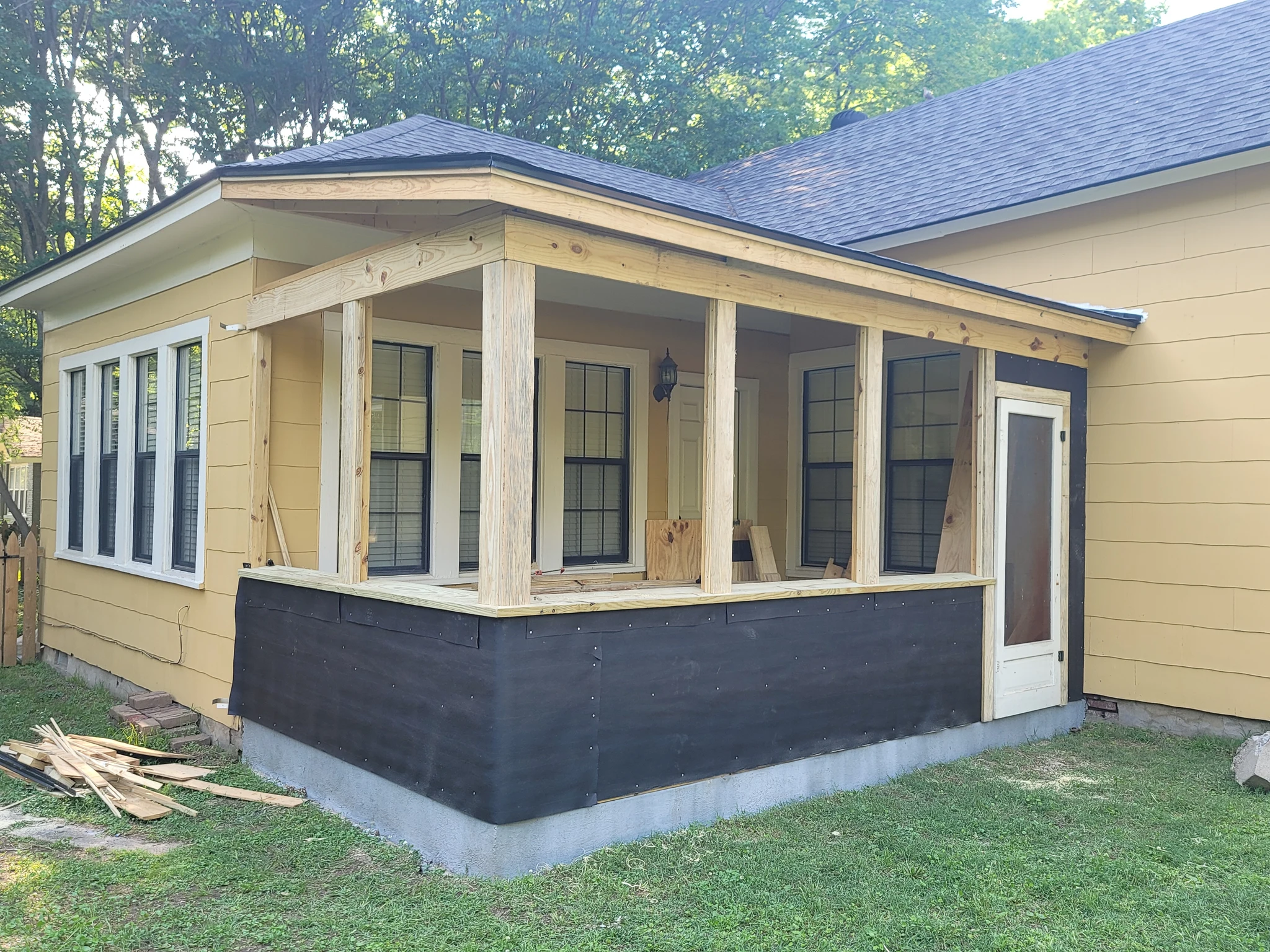 The porch exterior sheathed with a dark skirt and window openings framed.