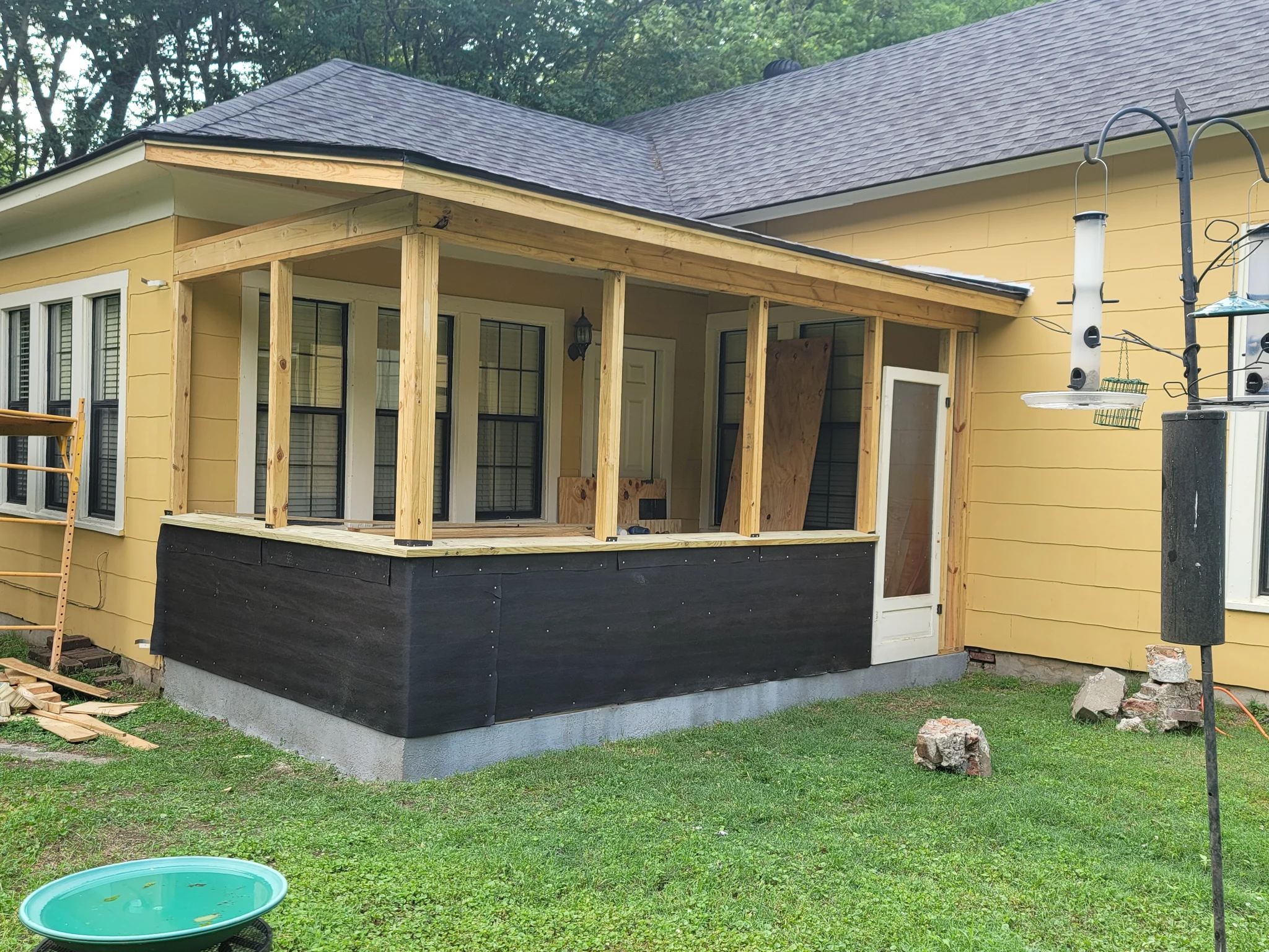 The completed screened porch on the yellow house, seen from the lawn.