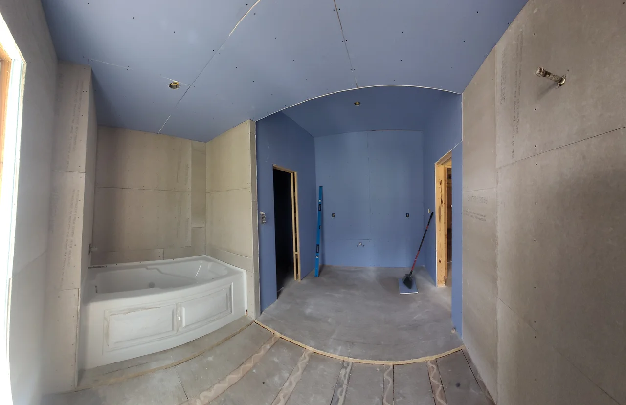 A bathroom with a vaulted ceiling and tub set in place.