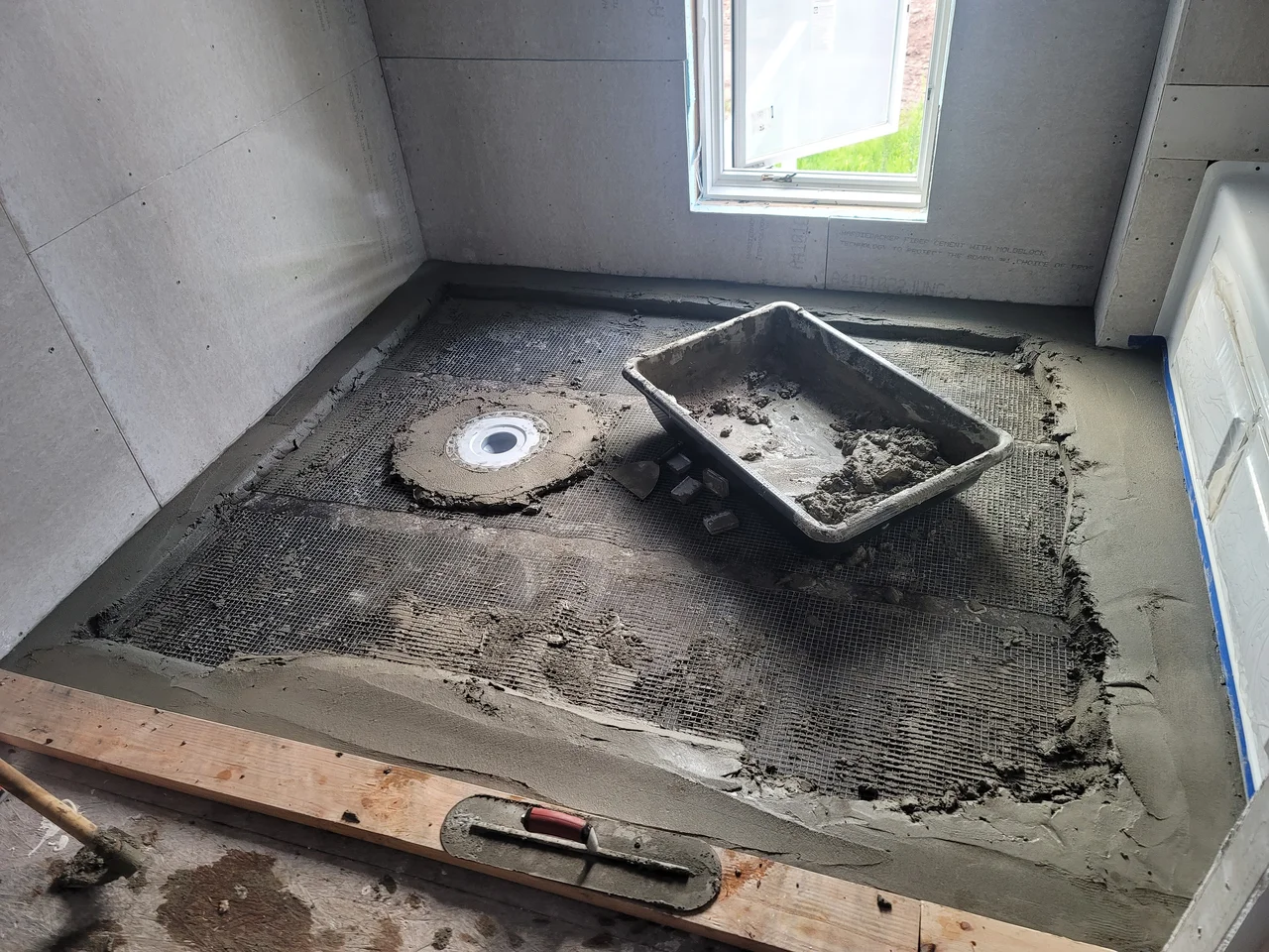 A mud-bed shower floor being floated to the drain.