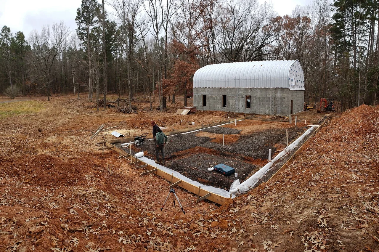 A cleared building site with footing forms laid out in red clay.