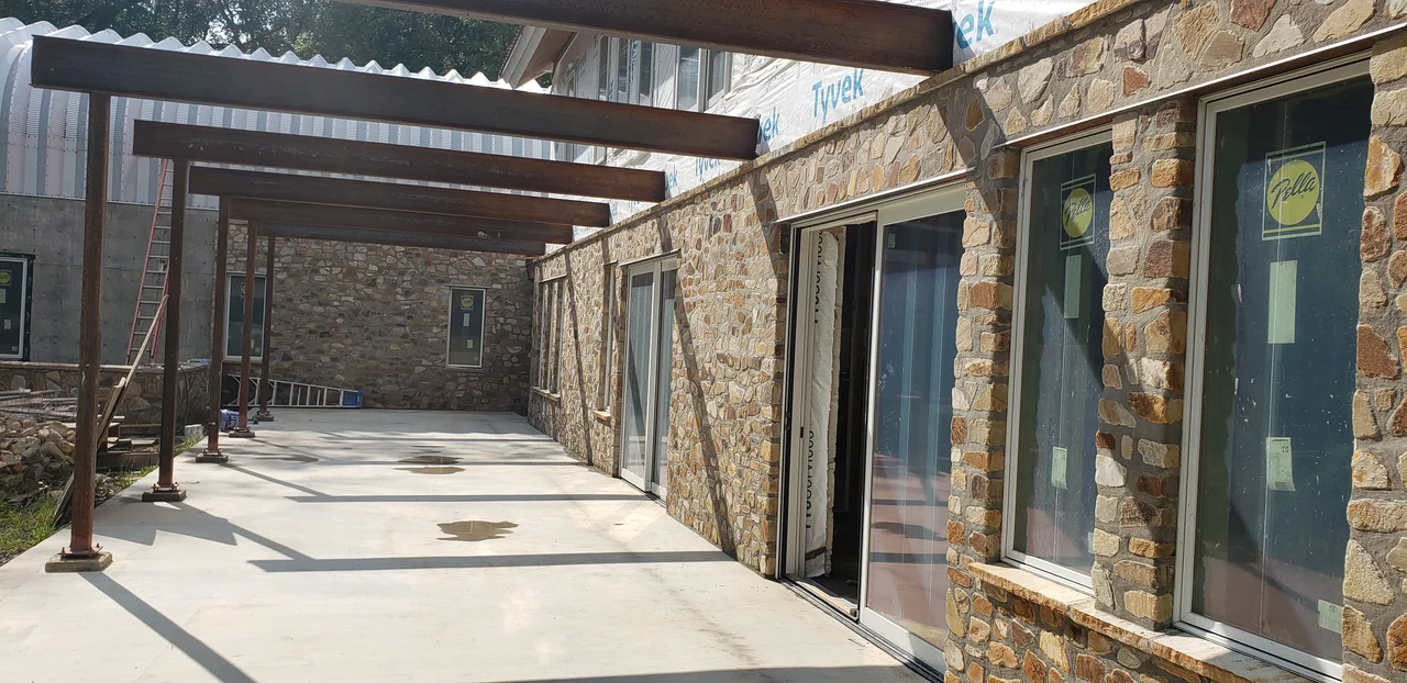 The covered walkway carried on steel beams between stone walls.