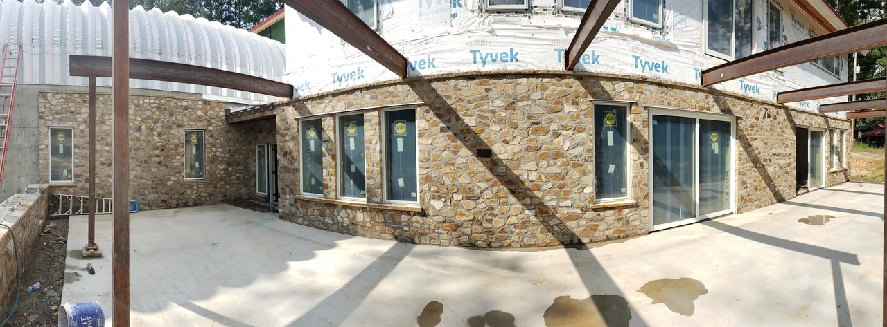 Wide view of the courtyard between the stone walls and the house.