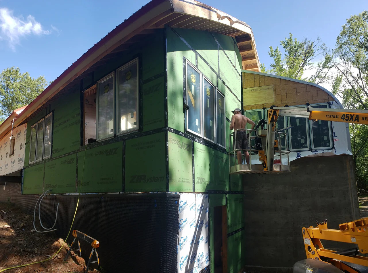The upper storey in green sheathing with windows set, a lift alongside and the arch roof running behind.