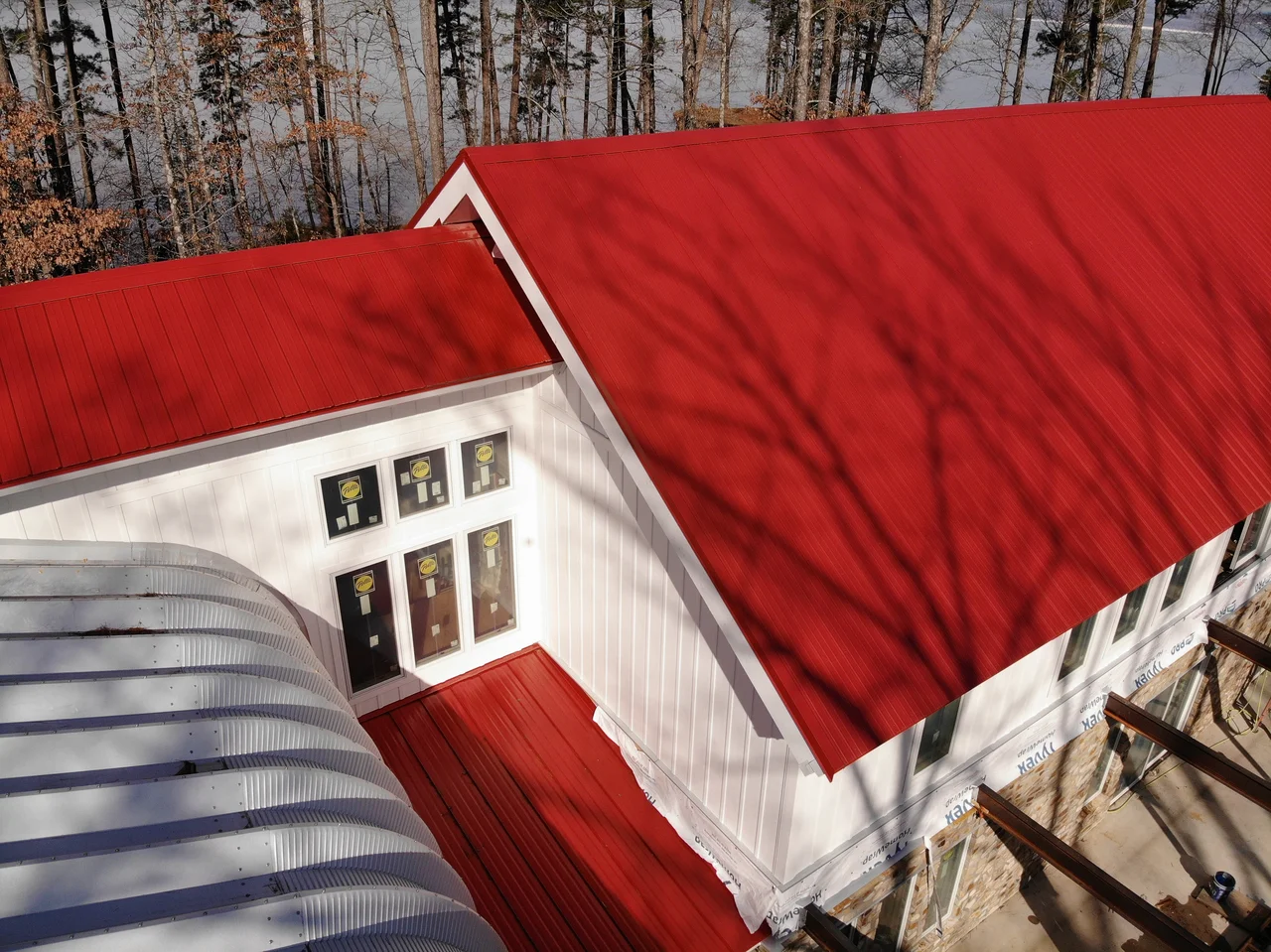 Aerial view of the red standing-seam roof meeting the white gable and the curve of the arch building.