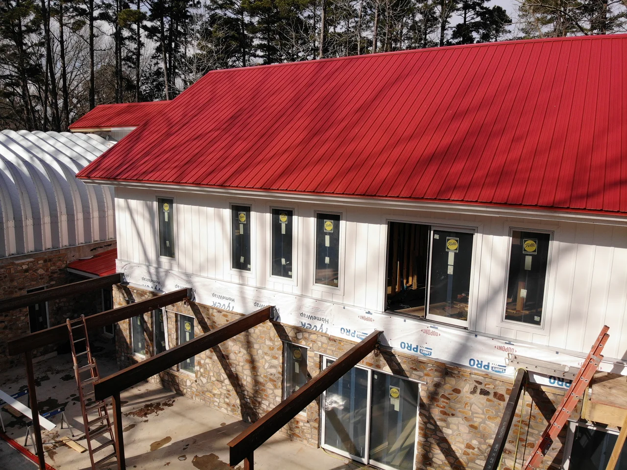 Aerial view along the roof and the run of upper-storey windows, steel posts standing below.