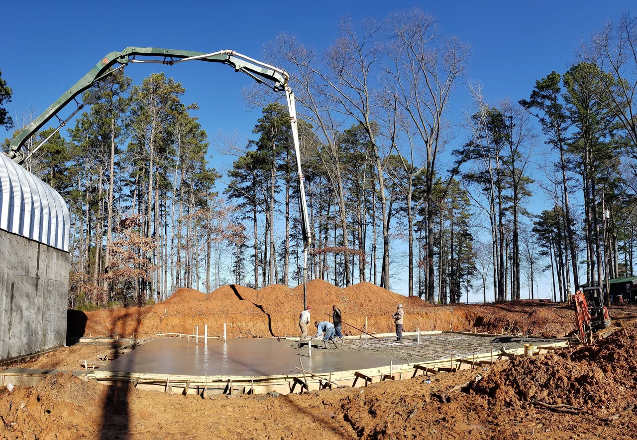 A concrete pump boom reaching over a formed slab with a crew working below.