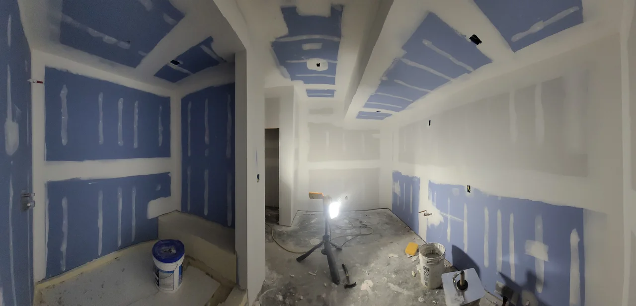Interior drywall hung and taped, with the vaulted ceiling following the roof above.