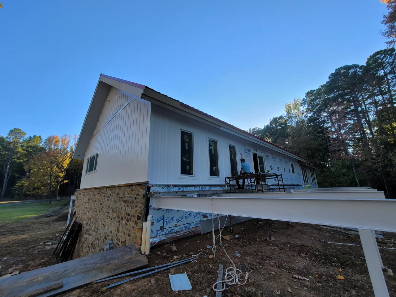 The low elevation running the length of the house, white siding above a stone base.