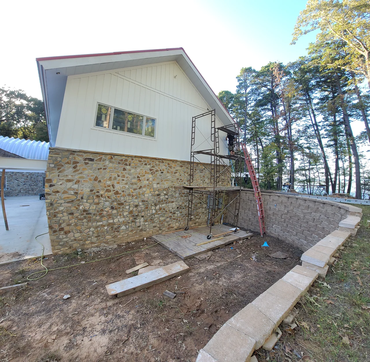 The concrete walk running along the stone wall beneath the house.