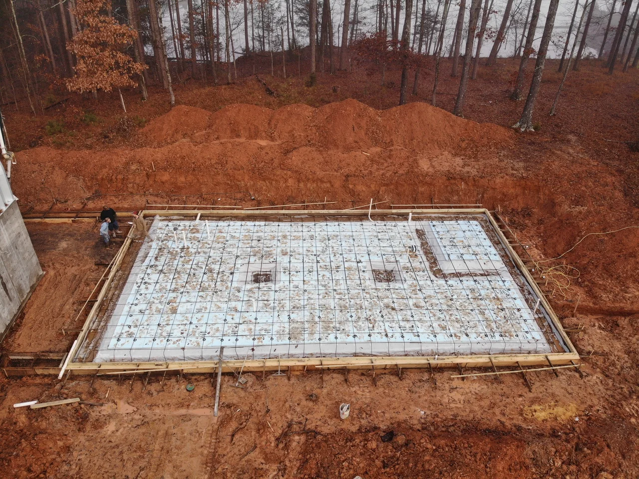 Aerial view of a rebar footing mat laid out across bare graded earth.