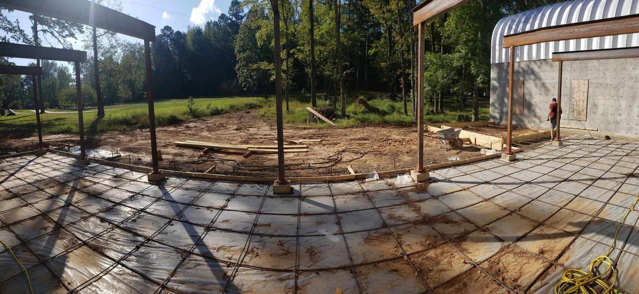 A poured slab with steel columns standing and the arch building beyond.