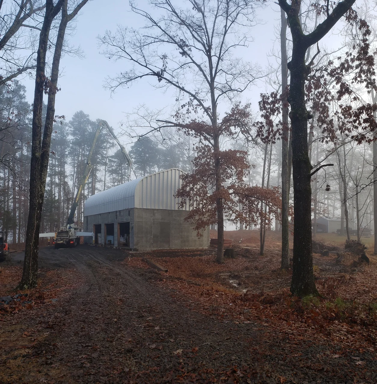 The bare concrete garage structure standing in leafless woods.