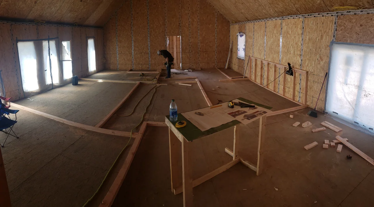 Interior of the upper level with plywood decking and window openings.